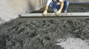 Operario alisando una solera de hormigón fresco antes de aplicar el molde impreso en una obra en España.