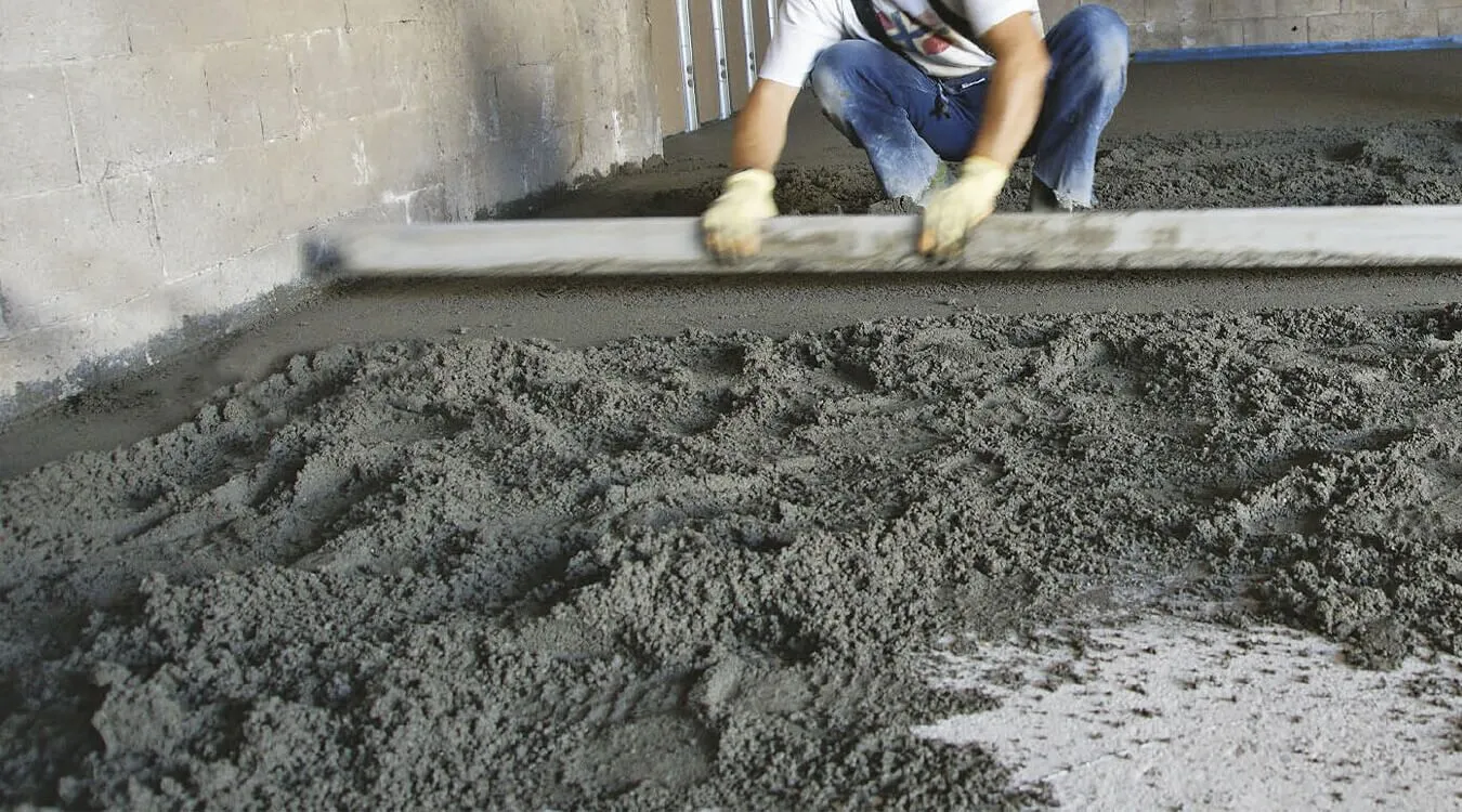 Operario alisando una solera de hormigón fresco antes de aplicar el molde impreso en una obra en España.